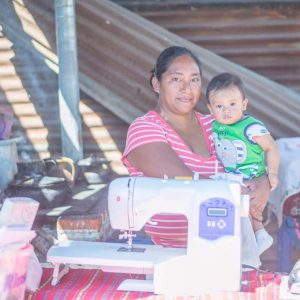 Ruth holding her son Timothy in her kitchen, where she also operated her sewing business before Fernando and Global Action helped build her sewing shop.
