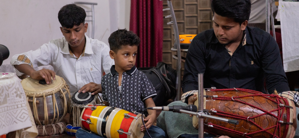 little boy playing drums with a band in india